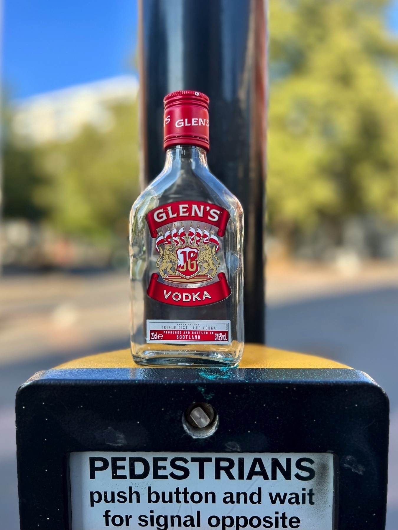 A small bottle of vodka on a pedestrian crossing sign in London. 